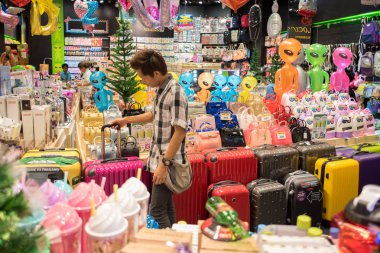 Bangkok, Tayland - 17 Aralık 2017: Genç Asyalı adam Mega Bangna Alışveriş Merkezi 'ndeki Viva Loco hediye dükkanında bir valizi yuvarlıyor. Megabangna Tayland 'ın en büyük alışveriş merkezlerinden biridir..