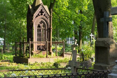 Saint Petersburg, Rusya - 22 Haziran 2020: Smolenskoye Lutheran mezarlığındaki yemyeşil bitki örtüsü arasında süslü bir mezar. Eskiden burası etnik Almanların ve diğer Batılıların gömüldüğü yerdi..