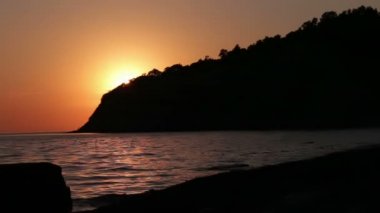 Dalgalar yavaşça sahilde yıkanmış ve güneş düşmeye başladığında sonra düşmeye.