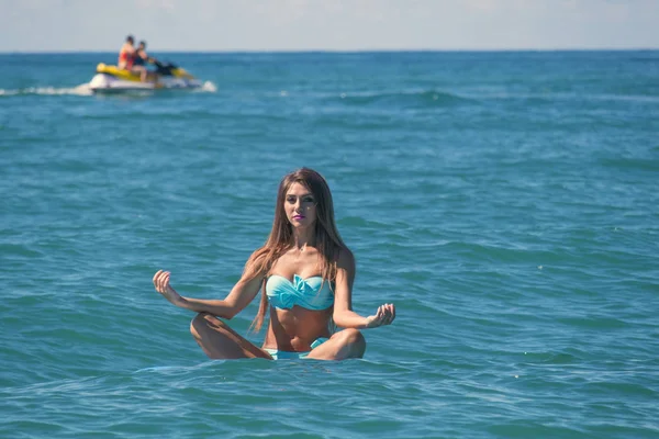 Kadın Sup yatılı bir lotus poz denizin üzerinde rahatlatıcı. Raket Pano Yoga. Doğa ile uyum içinde sağlıklı yaşam tarzı.