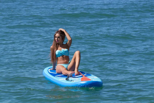Mujer relajándose en un SUP embarcado en el mar. Vida sana en armonía con la naturaleza . —  Fotos de Stock