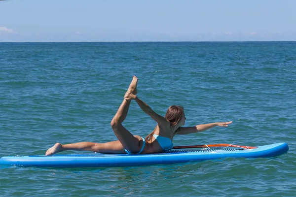 Kadın Sup yatılı denizin üzerinde rahatlatıcı. Raket Pano Yoga. Doğa ile uyum içinde sağlıklı yaşam tarzı.