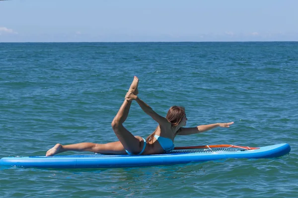 Woman relaxing on a SUP boarding in the sea. Paddle Board Yoga. Healthy lifestyle in harmony with nature. Stock Photo