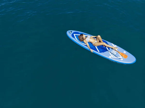 Um drone aéreo disparado. Mulher relaxando em um SUP embarque no mar. Paddle Board Yoga. Estilo de vida saudável em harmonia com a natureza . Fotografias De Stock Royalty-Free