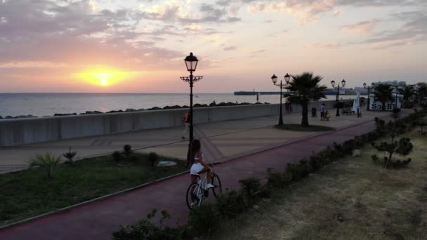 Luchtfoto vlucht met Dji drone over mooie jonge sexy brunette meisje met fiets op een achtergrond van de zee-zonsondergang — Stockvideo