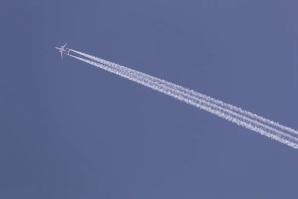 A fehér repülőgép repülni az égen, jet motor, hogy a fehér vonal a füst a kék ég, a design a szimbólum irányba. — Stock Fotó