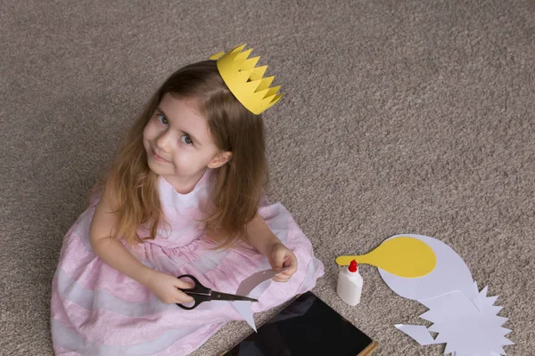 Chica bonita con un papel de tijeras corona. linda niña jugando con el arte y los materiales para la costura. Hecho a mano. espacio para texto — Foto de Stock