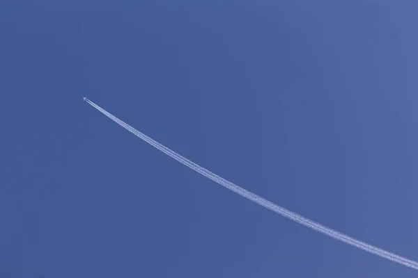 Beyaz uçak gökyüzünde uçmak, jet motoru tasarım yönü simge hakkında için mavi gökyüzünde duman beyaz çizgi yapmak. — Stok fotoğraf