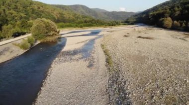bir ormanda dağ nehri üzerinde uçan drone görünümü