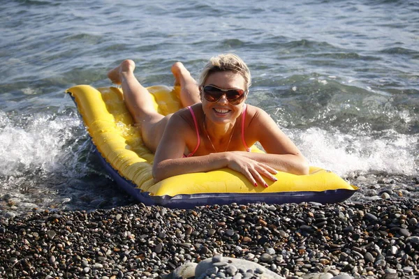 Happy woman smiling in sunglasses on an air mattress by the sea — Stock Photo, Image