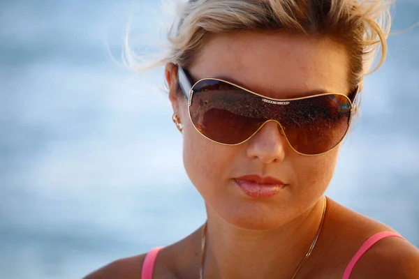 Retrato de cerca Hermosa mujer caucásica divirtiéndose en verano usando gafas de sol sobre fondo azul marino. Modelo mirando a la cámara . —  Fotos de Stock