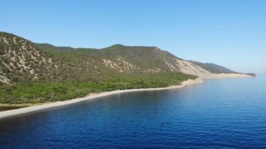 İHA 'dan panorama atışı. Deniz kenarındaki çam ormanlarıyla kaplı güzel dağlar. Güneşli bir yaz günü. 4k