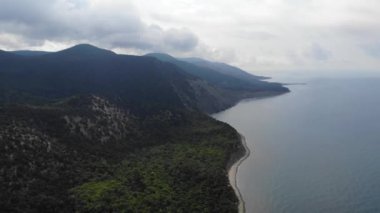 Sahil şeridi boyunca uçuş. Geriye dönük kamera hareketi. DJI ile güzel yeşil dağlar ve beyaz kumlu plajda yapılan hava uçuşu. 4k