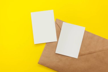 büyük kahverengi zarf üzerinde sarı bir arka plan ile iki boş kartpostal. Boşaltmak, flatlay, mockup tasarım için