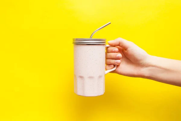 El ile bir metal kap ve bir saman sarı bir arka plan üzerinde pembe bir kupa ile. Tasarım, metin için yer için alay