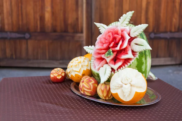 Holiday buffet tabble with carving on watermelon, melon and apples in the metal tray. Ideas for decoration, event atmosphere