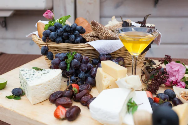 cheese, honey, bread, grapes and figs on the table decorated with flowers, leaves and strawberries. Ideas for decorating. wedding party