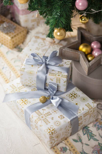 Beautiful silver and gold boxes with gifts under the Christmas tree