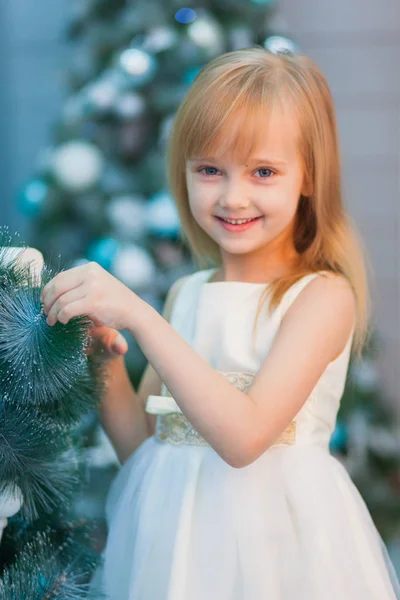 Beyaz elbiseli güzel çocuk Noel ağacı süsle, hediye açar