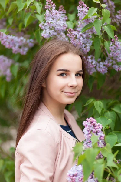 Młoda piękna dziewczyna stoi w pobliżu krzewów kwitnącej bzu — Zdjęcie stockowe