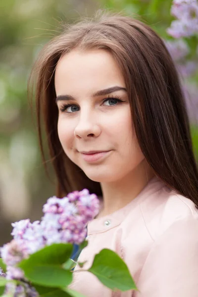 Молода красива дівчина стоїть біля кущів квітучого бузку — стокове фото