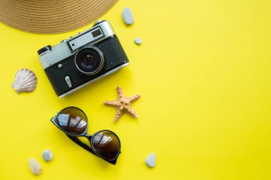 Vintage kamera, şapka, mayo, sarı arka plan üzerinde güneş gözlüğü. Yaz konsepti. Flatlay, copyspase