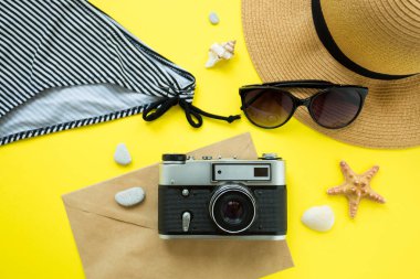 Vintage kamera, şapka, mayo, sarı arka plan üzerinde güneş gözlüğü. Yaz konsepti. Flatlay, copyspase