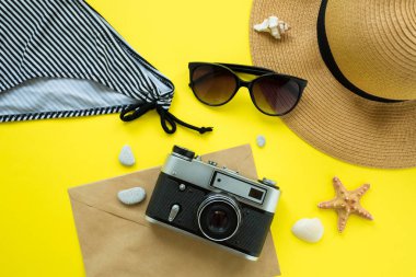 Vintage kamera, şapka, mayo, sarı arka plan üzerinde güneş gözlüğü. Yaz konsepti. Flatlay, copyspase