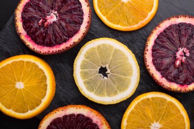 Taze taze sitruslar. Limonlar, kırmızı portakallar ve koyu taş arka planda portakallar. Boşluğu kopyala