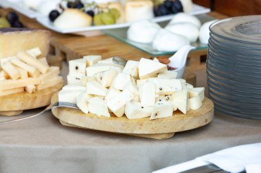 Dilimlenmiş peynir, yumuşak peynir ve peynir de dahil olmak üzere çeşitli peynir türlerini sunan tahta kesme tahtaları, üzüm ve ekmekle birlikte cazip bir açık büfe gösterisi yaratıyor.