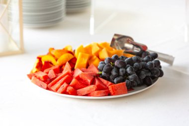 Büfe masasında servis edilen karpuz, kavun, şeftali ve üzümler de dahil olmak üzere bir tabak taze meyve.