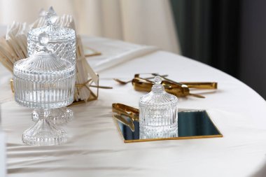 Kristal şeker kavanozları ve masaya yerleştirilmiş altın servis aletleri zarif bir atmosfer yaratır.