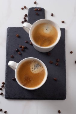 iki beyaz bardak kayrak üstte siyah kahve ile vie