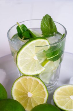 , mojito limonlu su içmek ve cam yakın beyaz zemin üzerine nane
