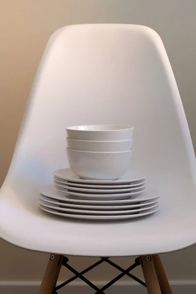 set of white dishes on a white chair