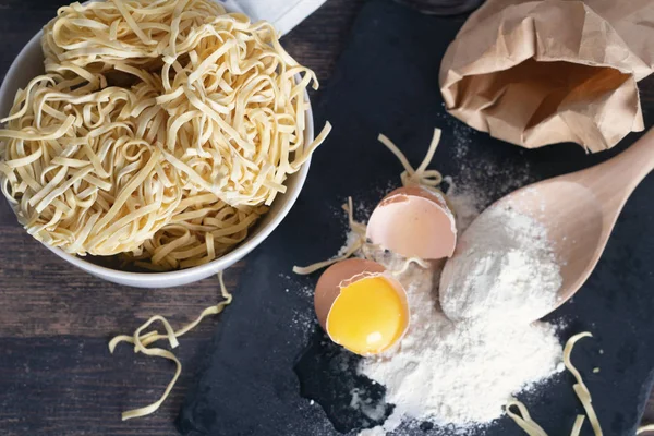 broken egg, flour and egg noodles on a wooden table