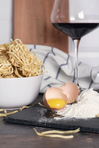 broken egg, flour and egg noodles and a glass of red wine on the kitchen table