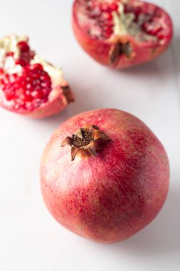 Kırmızı nar ve nar taneleri beyaz mermer zemin üzerinde