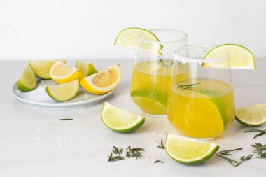 Beyaz arka planda tuz ve turunçgiller olan bir bardakta limon içeceği