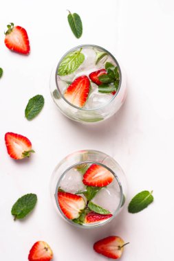 Kadehler çilekli ve beyaz arka planda taze nane şekerli.