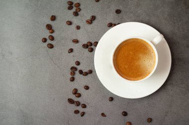 Arka planda fasulye olan bir fincan kahve.