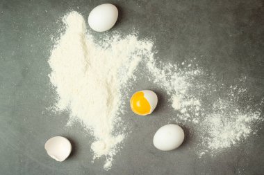 Kırık yumurta ve un siyah bir arkaplanda