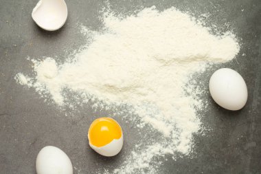 Kırık yumurta ve un siyah bir arkaplanda