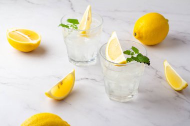 Beyaz arka planda buzlu ve limonlu cam kadehler.
