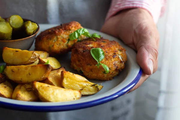 Erkeklerin elinde fırında patates ve tavuk pirzolası