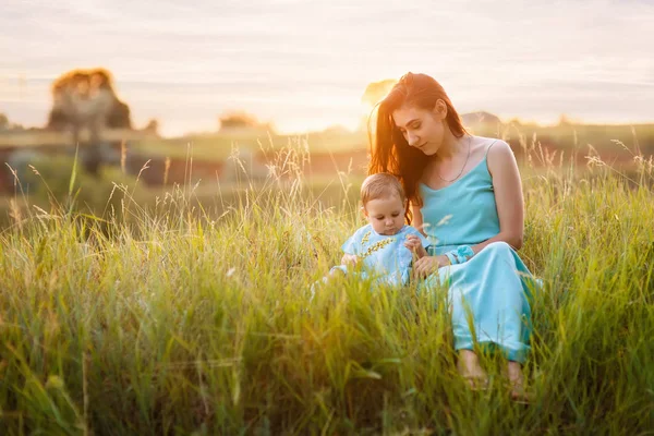 Matka s malou dcerou sedí na louce — Stock fotografie