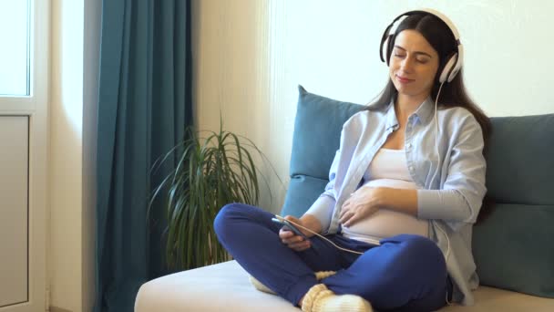 Pregnant woman listening music in headphones — Stock Video