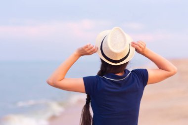 deniz kumsalda arkadan görünüşü kız elbise ve şapka ayakta. Yaz tatil kavramı