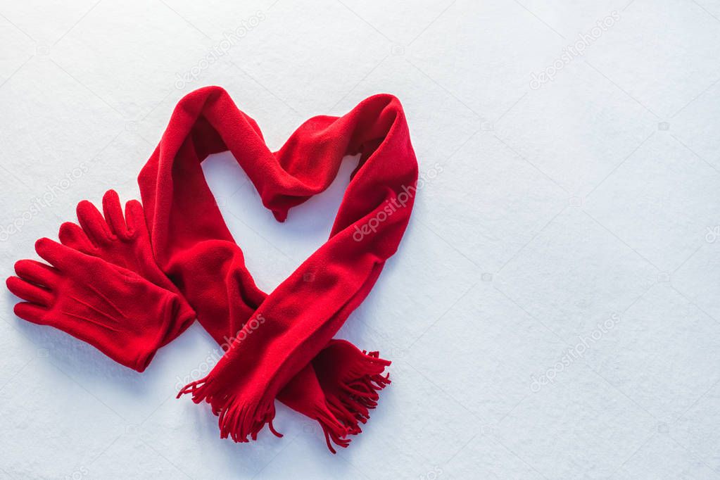 red gloves and scarf as heart on snow