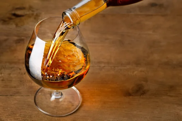 Brandy o coñac vertiendo en el vaso — Foto de Stock